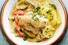 a white plate topped with chicken, pasta and veggies on top of a table