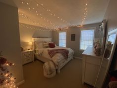 a bedroom decorated for christmas with lights strung from the ceiling and bed in the corner