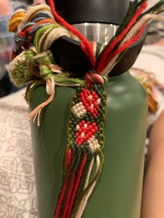 a close up of a green water bottle with some colorful thread on it's handle