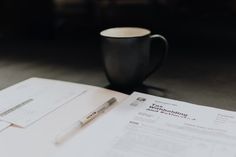 a coffee cup sitting on top of a table next to papers