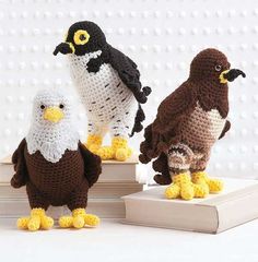 three crocheted stuffed birds sitting on top of books