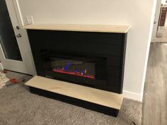 a fire place in the middle of a living room with carpeting and white walls