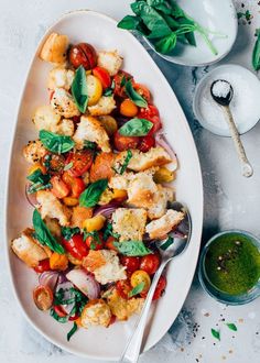 a white plate topped with chicken and veggies next to a bowl of pesto