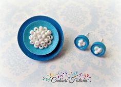 there is a blue plate with white beads on it and two ear pins in the shape of snowflakes