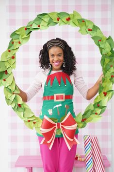 a woman standing in front of a wreath with paper decorations around her waist and arms