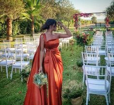 a woman in an orange dress standing next to rows of white chairs