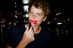 a man with red lipstick on his face is holding a brush in front of his mouth