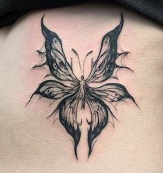 a black and white butterfly tattoo on the back of a woman's stomach,