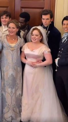 a group of people standing next to each other in front of a door wearing formal clothing