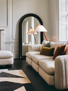 a living room filled with furniture and a large mirror on the wall next to it