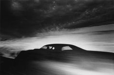 a black and white photo of a car in motion