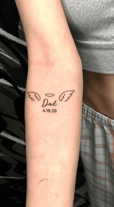 a person with a tattoo on their arm that has two angel wings and the number zero