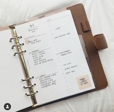 an open planner book sitting on top of a bed