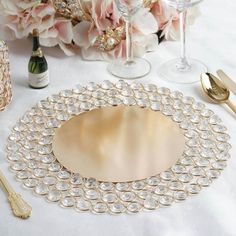 a table topped with plates and glasses filled with flowers next to wine glasses, champagne flutes and goldware