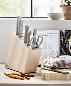 an assortment of kitchen utensils sitting on top of a counter next to a book