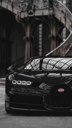 a black bugatti is parked in front of some stairs