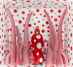 a woman standing in front of a red and white sculpture