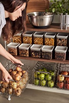 a woman picking up apples from a shelf