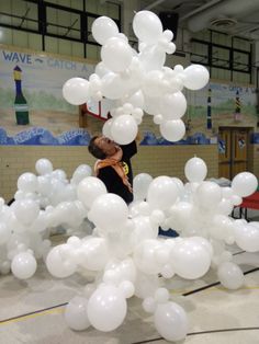 there is a woman that is holding balloons in her hand and standing next to a bunch of white balloons