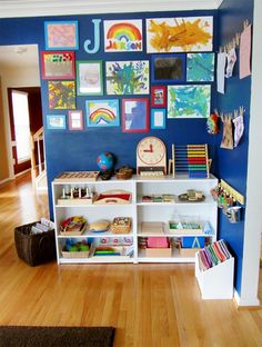 a child's playroom with blue walls and pictures on the wall behind it