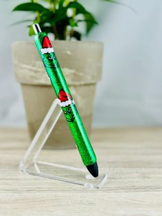 a green pen sitting on top of a wooden table next to a potted plant