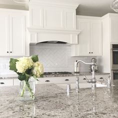 a vase with flowers sitting on top of a kitchen counter next to an oven and microwave