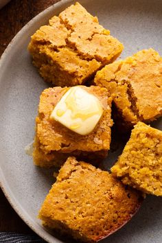 four pieces of pumpkin bread on a plate with butter in the middle and one bite taken out