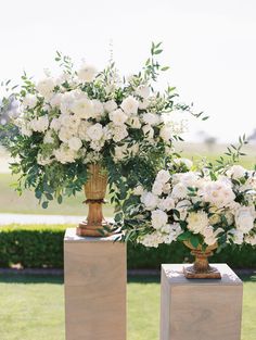 two vases filled with white flowers on top of blocks