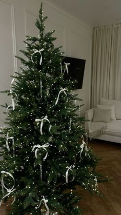 a decorated christmas tree with white ribbons