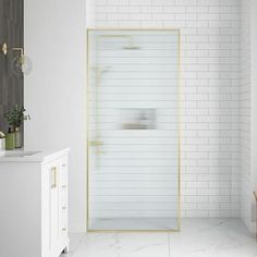 a bathroom with white tile and gold accents