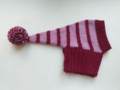 a knitted hat with a pom - pom attached to the side on a white surface