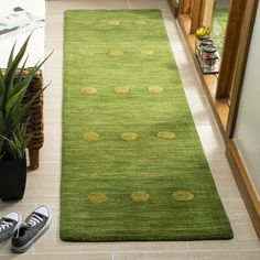 a green rug with yellow polka dots is on the floor next to a pair of sneakers