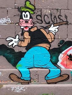 graffiti on the side of a brick wall with a cartoon character holding a baseball bat