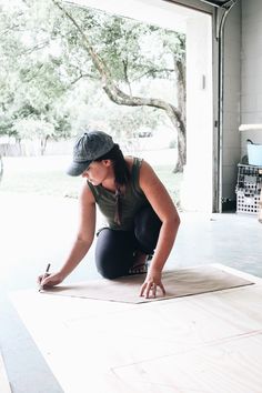 a woman kneeling on the floor with her hands in front of her face while drawing