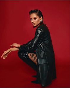 a woman sitting on the ground with her legs crossed, wearing black leather clothes and stockings