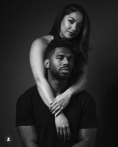 black and white photograph of a man holding a woman on his back in front of a dark background