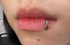 a close up of a woman's lip with a ring on it and the tip of her nose