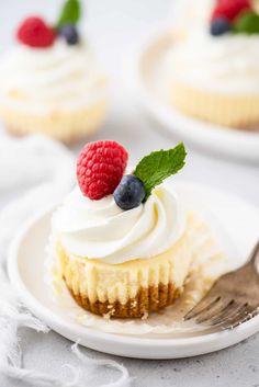 a white plate topped with cupcakes covered in frosting and raspberries