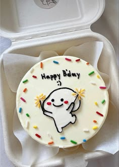 a birthday cake in a white box with sprinkles and an elephant on it