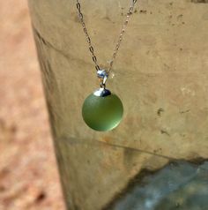 a green glass ball is hanging from a chain on a metal container with water in it