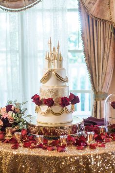 a three tiered wedding cake with roses on the table