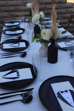 the table is set with black and white plates, napkins, and vases