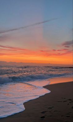 the sun is setting at the beach with waves coming in