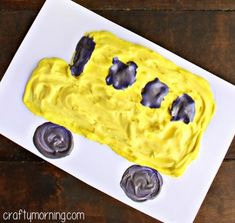 a cake made to look like a car with yellow frosting on it and wheels