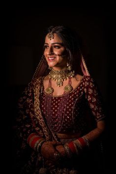 a woman in a red and gold outfit with jewelry on her neck, smiling at the camera