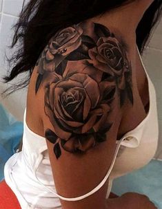 a woman's shoulder with black roses tattoo on her left arm and the bottom half of her body