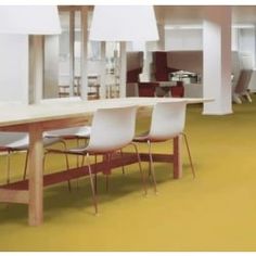 an office with yellow flooring and white chairs around a long table in the center