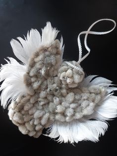 a white feather ornament hanging from a string on a black surface with beads