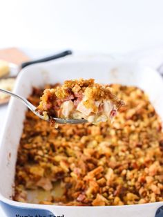 a spoon full of food is being lifted from a casserole dish with crumbled toppings