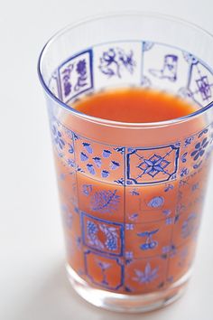 a shot glass filled with orange juice on top of a white table